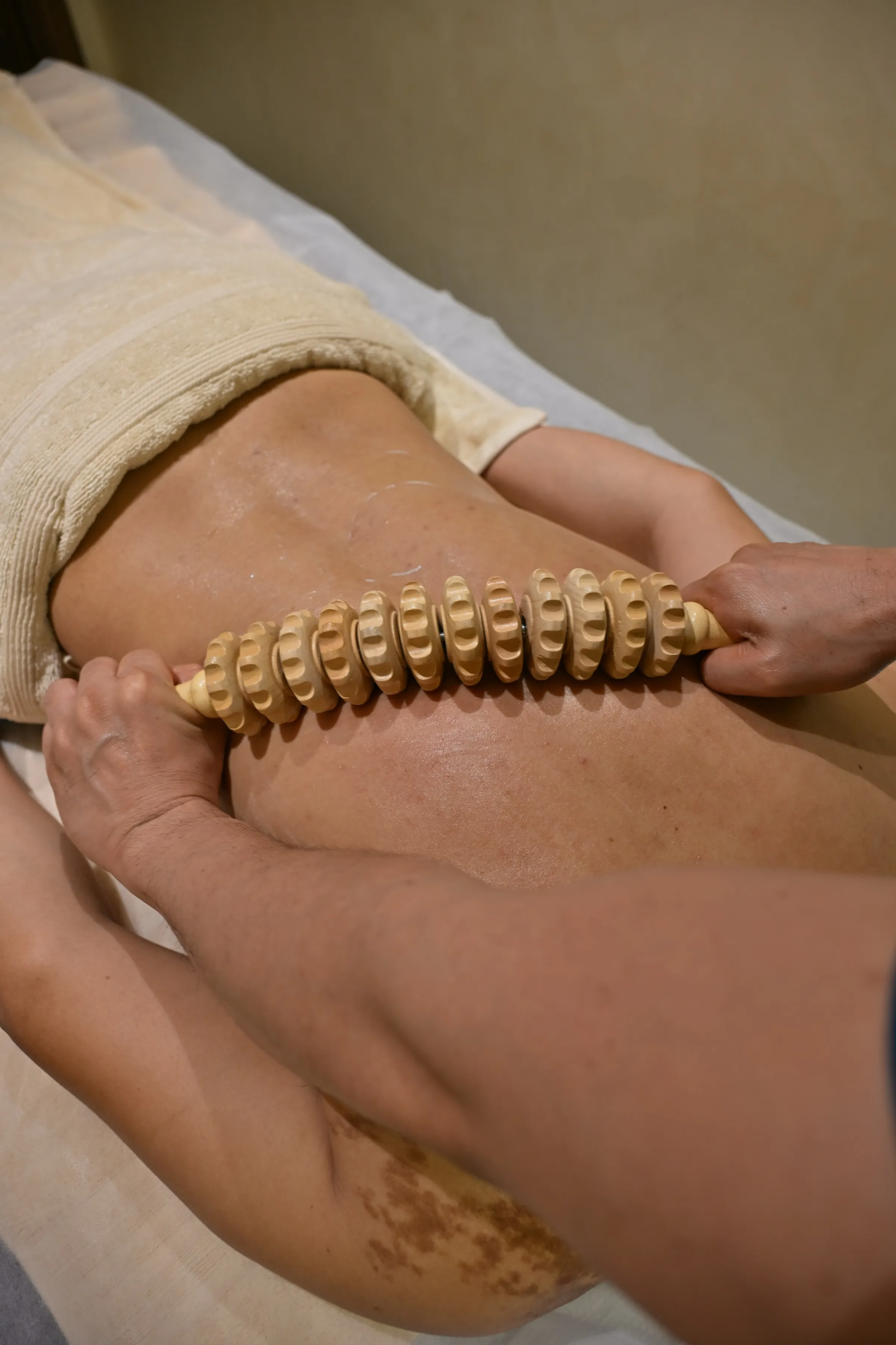 Therapist working a wooden Madero roller along a client’s back