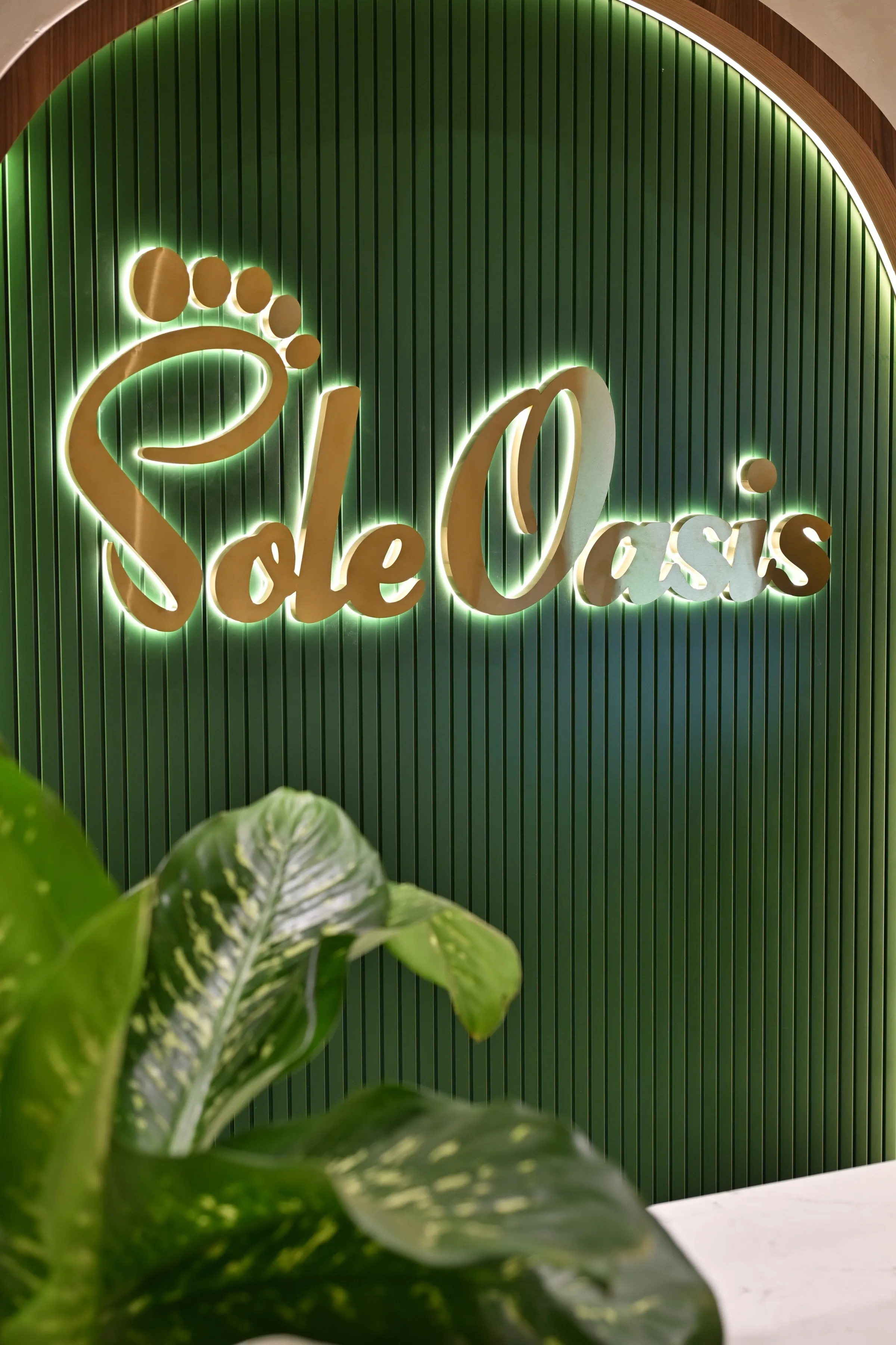 Backlit gold Sole Oasis wordmark on the fluted green arch