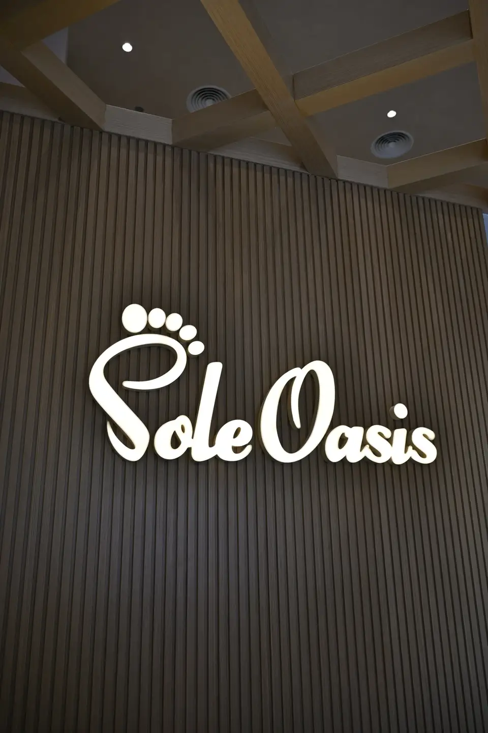 Illuminated Sole Oasis sign glowing above the marble reception